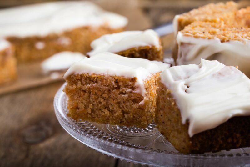 A glass dish with a vanilla and pumpkin spice cake with white icing