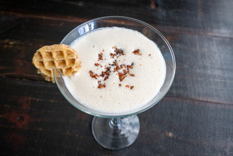 A martini glass with a maple syrup cocktail that has been garnished with a waffle