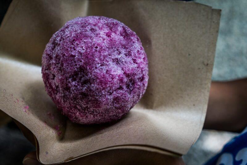 A piece of cloth with a purple ball of ice, highlighting the idea of a grapeade snow cone