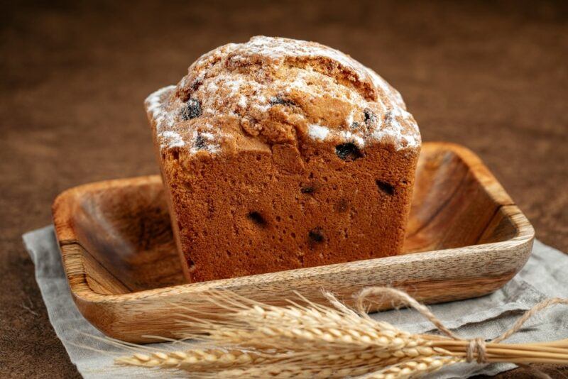 A wooden tray containing a holiday cake called stolichny with some wheat in the foreground