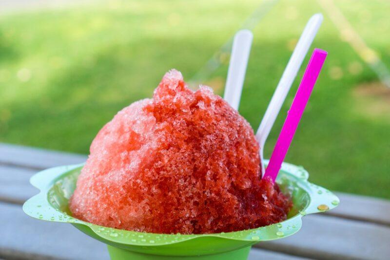 A light green container that holds a warheads snow cone