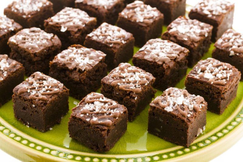 A lime green plate with small chocolate brownies shaped like squares