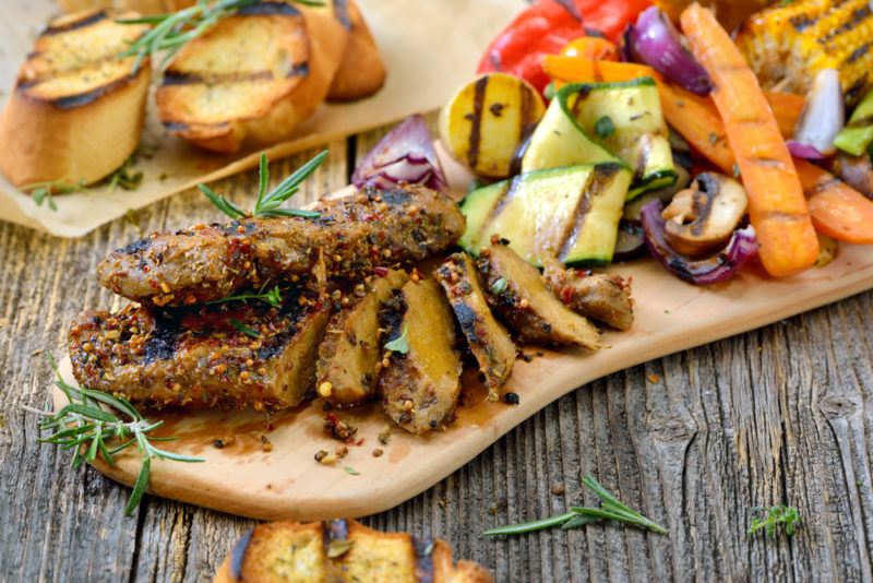 A grilled seitan steak on a table with vegetables