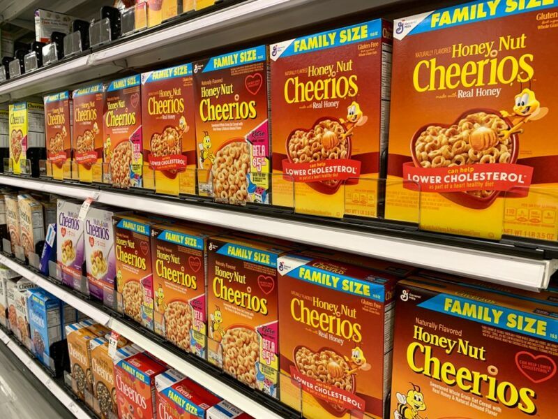 A grocery store shelf containing many boxes of Honey Nut Cheerios