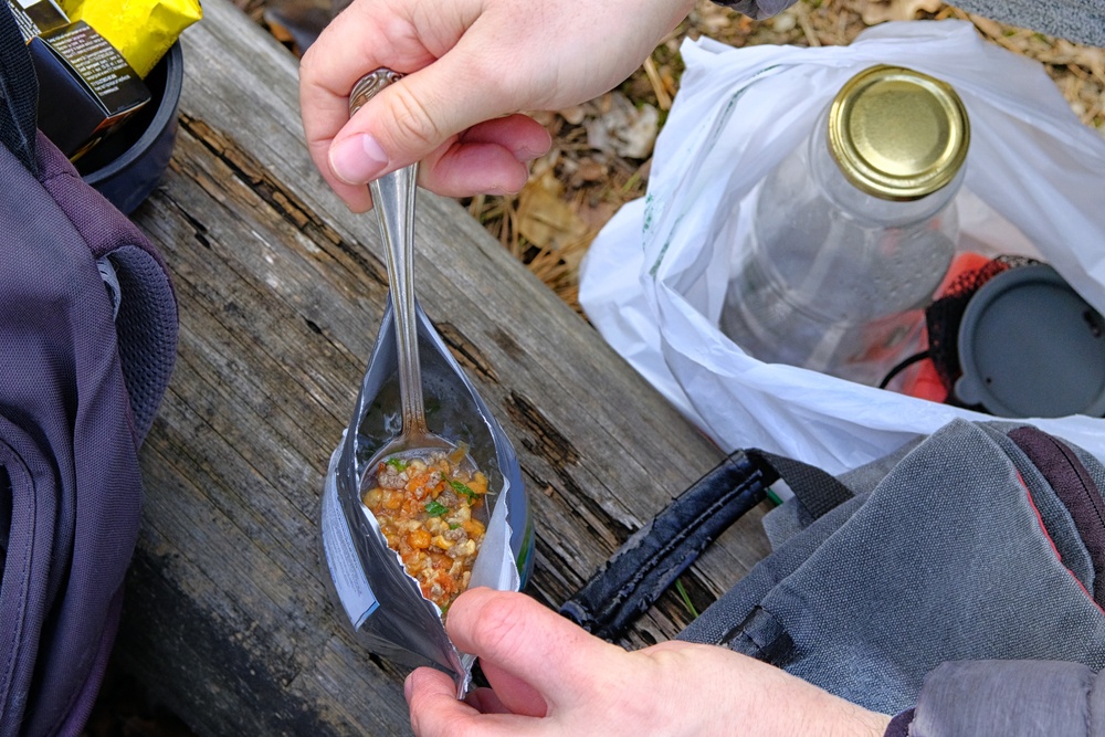 A hiker eating a dehydrated hiking meal