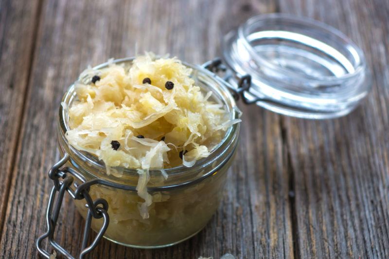 A glass jar containing saeurkraut on a wooden table