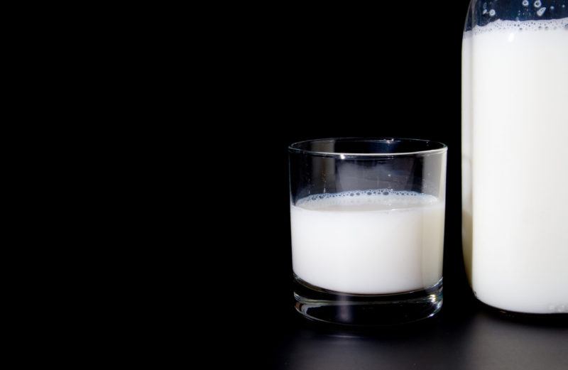 a pitcher and glass filled with skim milk