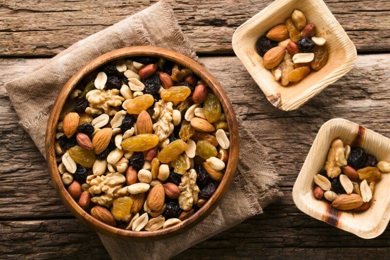 A large bowl with a nut based trail mix, next to two small bowls with the same trail mix