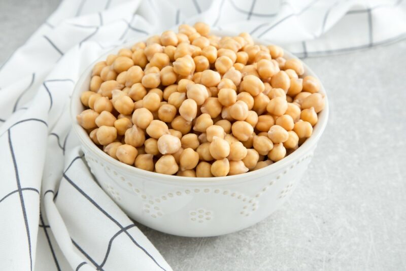 A large white bowl of chickpeas next to a checkered cloth