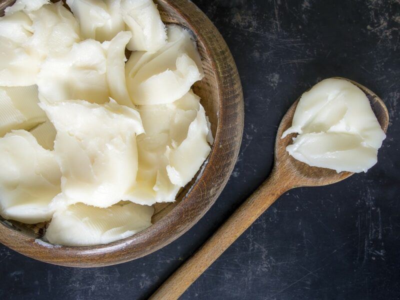 A large dish of shortening with a wooden spoon of lard next to it