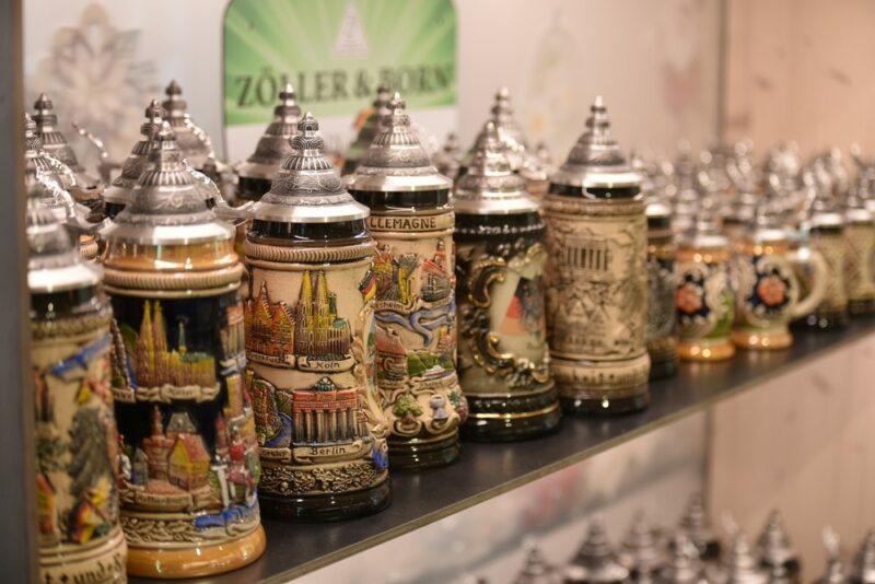 A collection of different German beer steins behind glass in a store