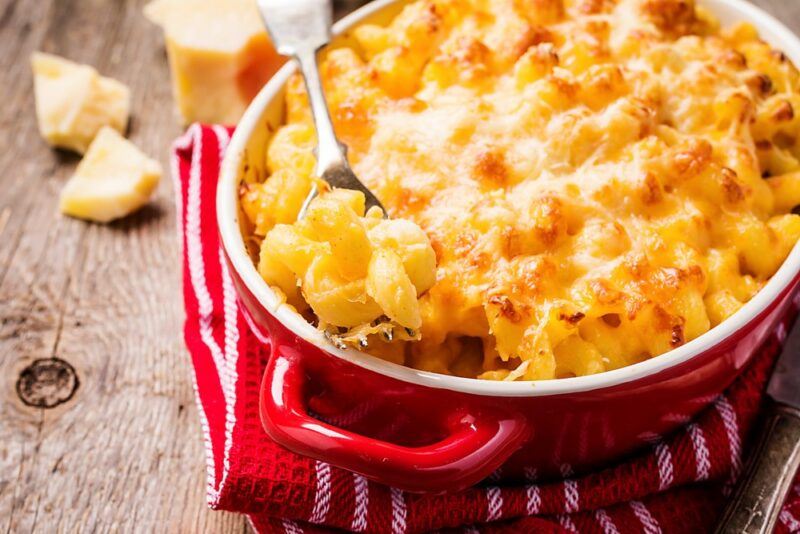 A red dish containing baked mac and cheese with a spoon