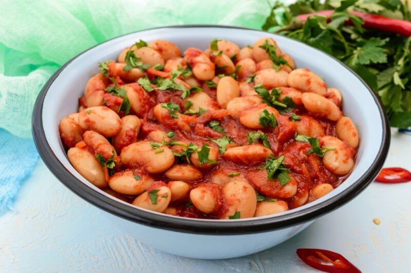 A black and white bowl containing plenty of white beans with sauce