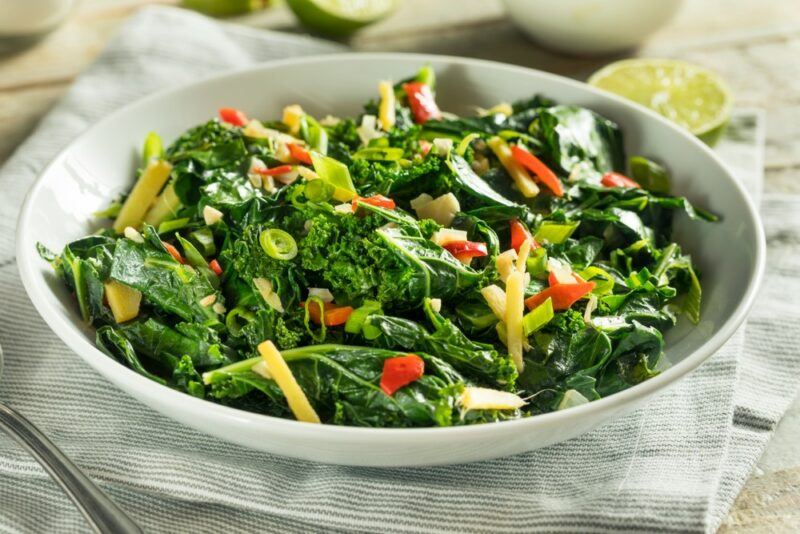 A large dish of collard greens with peppers and some other vegetables