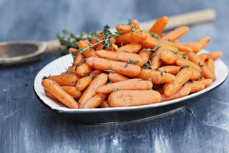 A shallow blue and white dish filled with carrots and herbs