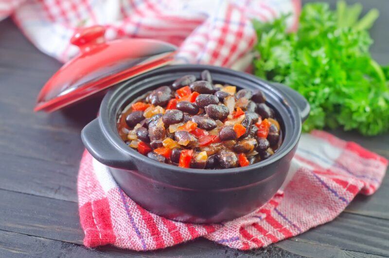 A large black dish that contains black beans, peppers, and other healthy ingredients