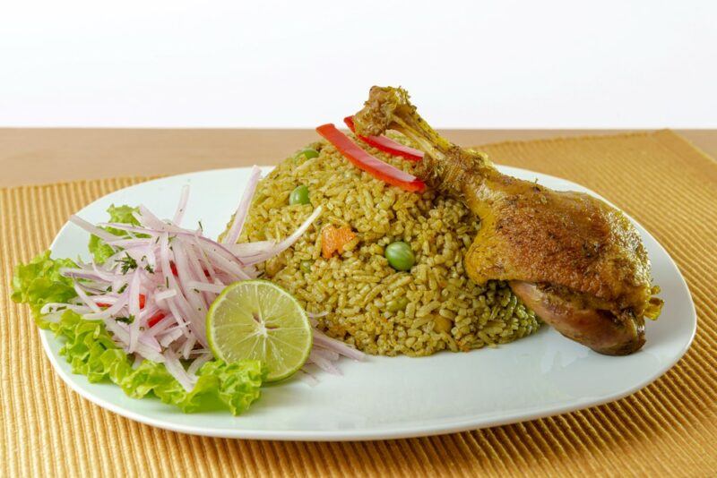 A white plate with fried rice and duck, called arroz con pato