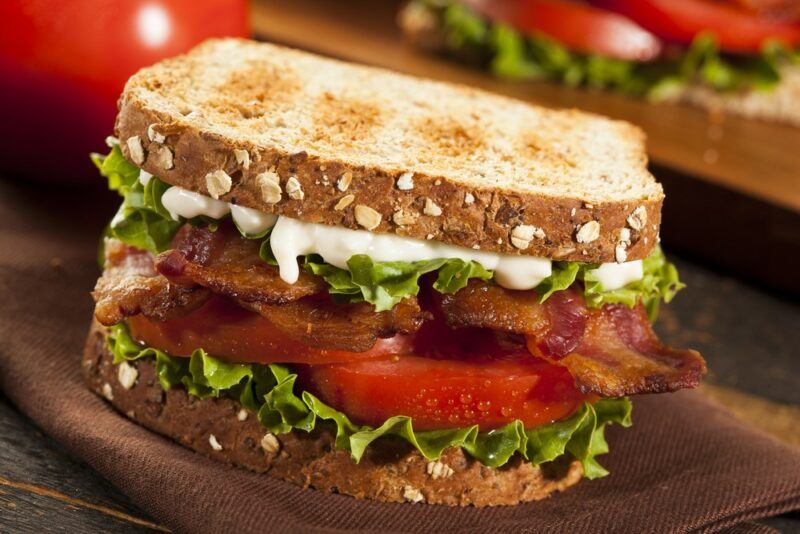 A large toasted sandwich with lettuce, tomato, bacon, and mayo