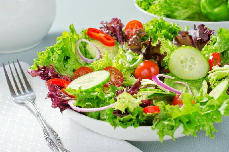 A large white bowl with lettuce, cucumber, and other vegetables