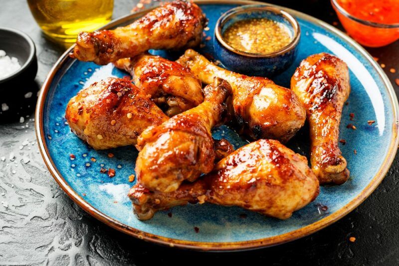 A light blue plate with cooked chicken drumsticks and dip