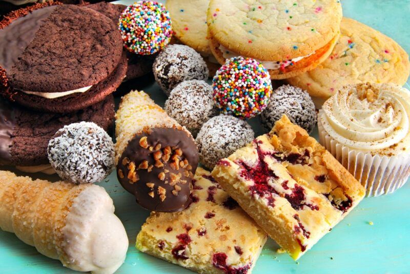 An aqua blue table with a collection of sweet treats, including cookies, pastries, bliss balls and muffins