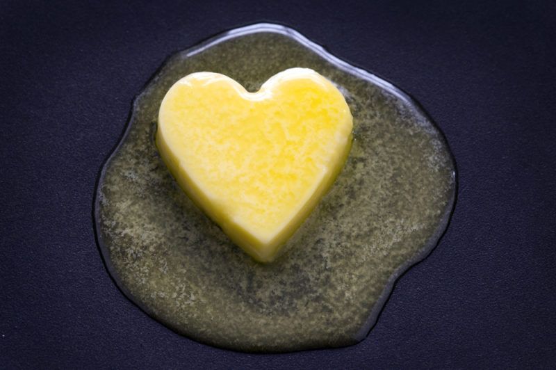 A pat of butter in the shape of a heart that's melting in a frypan