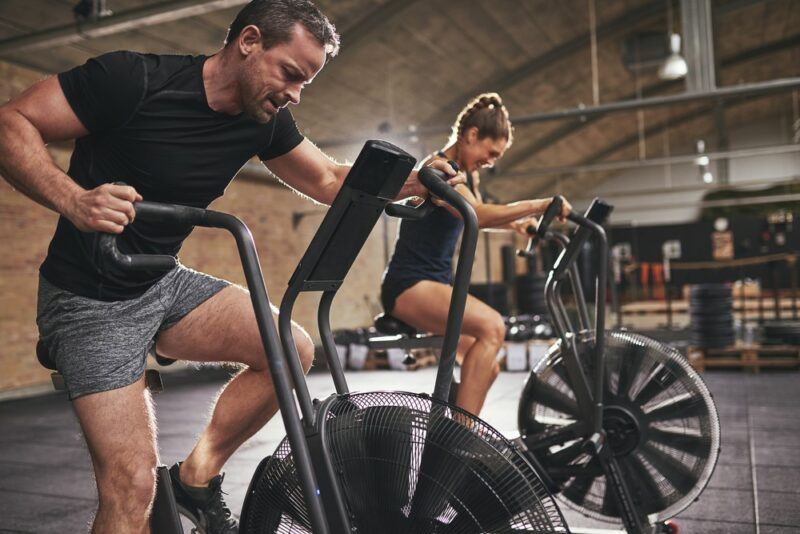 A man and woman exercising in a gym using bikes