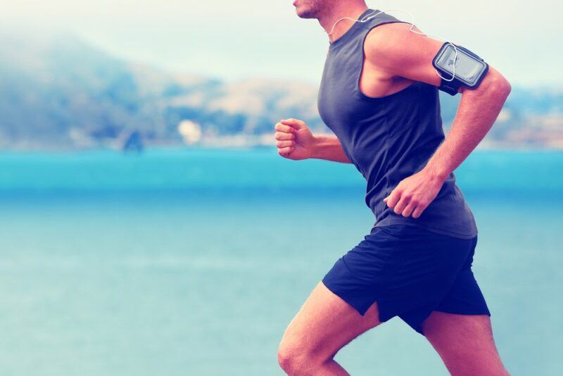 A man running outside using a phone to track his activity