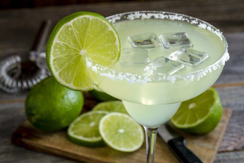 A large glass of margarita with a salt rim and a slice of lime