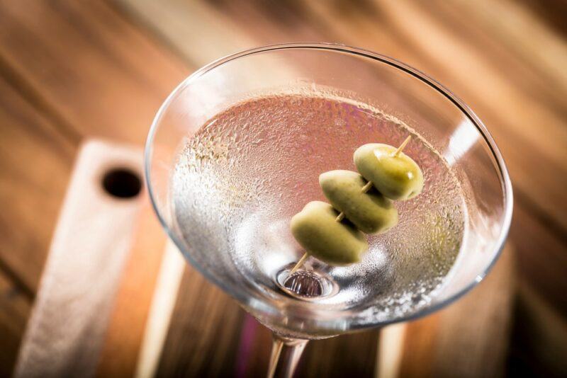 A martini called Damn it Jimmy garnished with olives on a wooden table or board