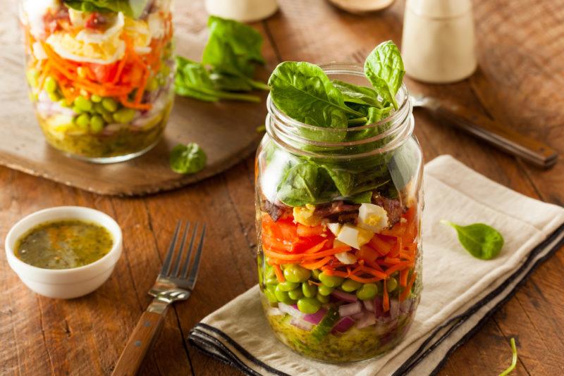 A salad built in a mason jar, with another similar salad in the background