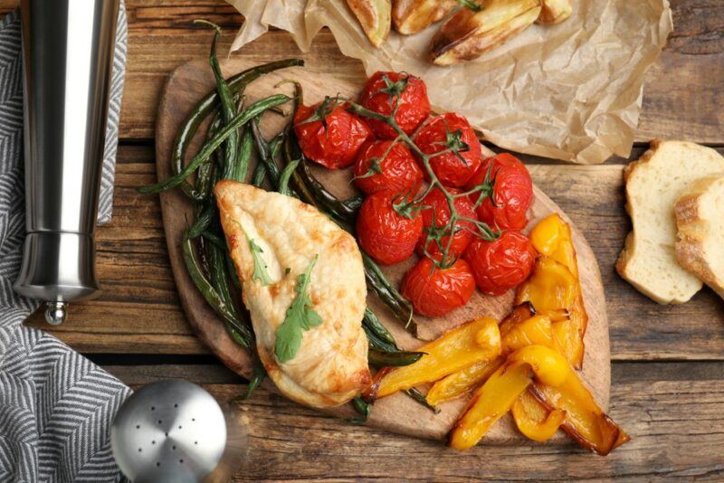 A plate with a full air fryer meal, including tomatoes, beans, chicken, and bell peppers