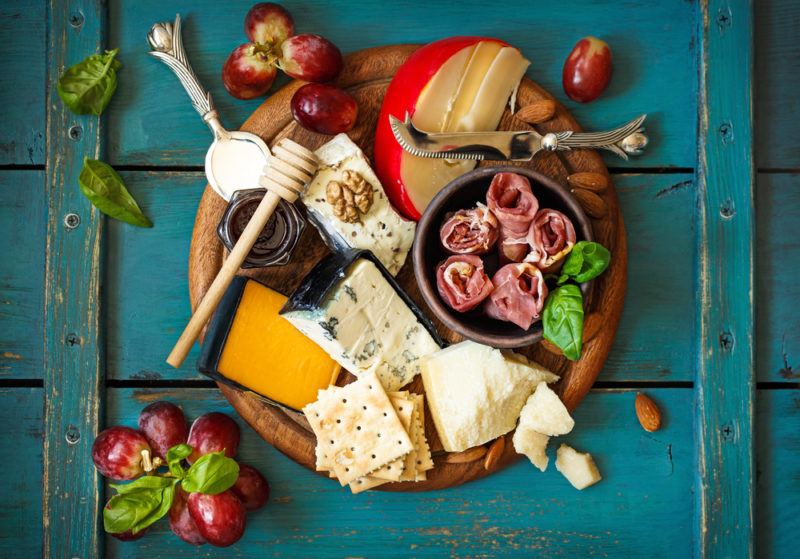 A meat and cheese board | Food For Net A wooden board with cheese, meat, and fruit