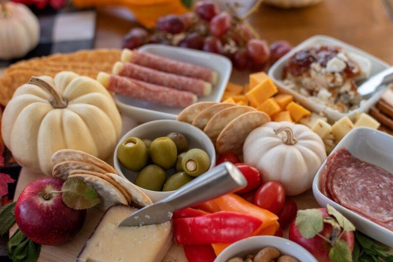 The ingredients for a meat, cheese, and olives board, with pumpkins for a winter or fall picnic