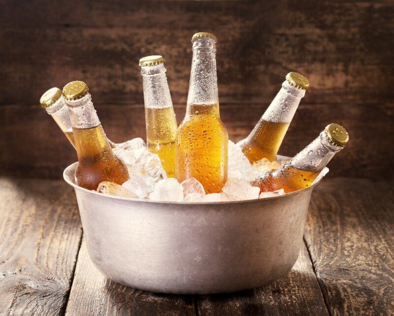 A metal bowl containing ice and six bottles of beer