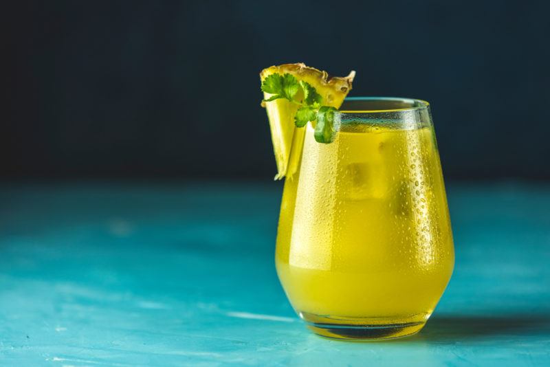 A glass of mezcalita cocktail on a blue table or bar against a dark background