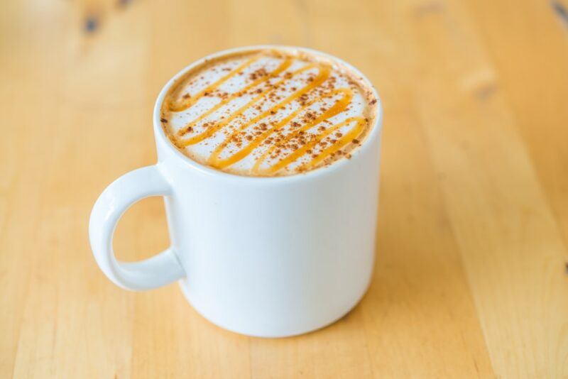 A white mug that contains a salted peanut butter hot chocolate cocktail with caramel drizzle on top