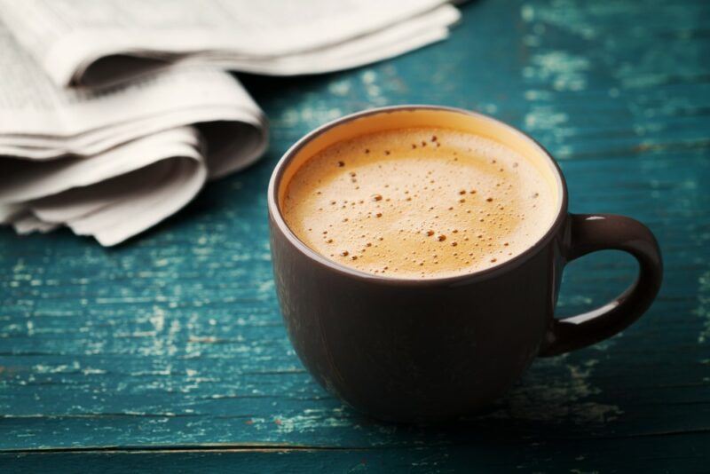 A blue table with a mug of coffee and a napkin