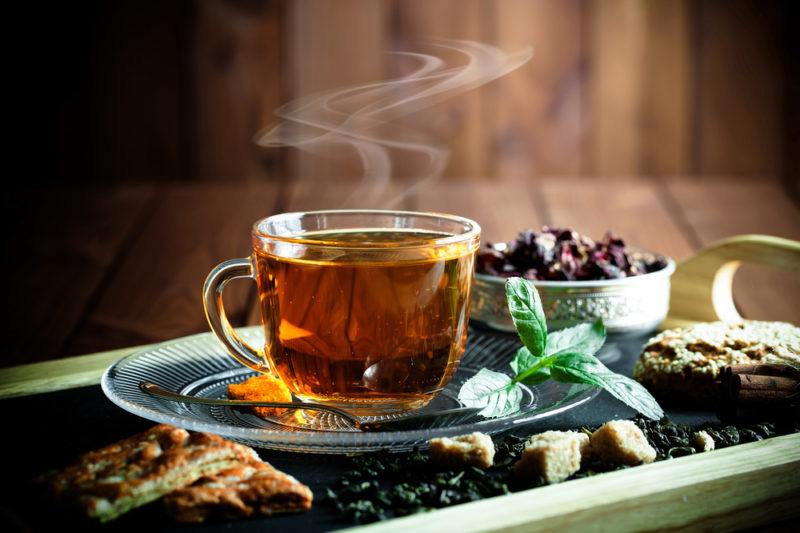 A mug of hot tea on a tray with tea leaves