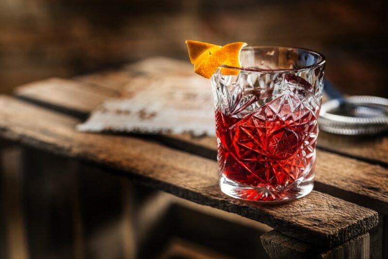 A single glass of a negroni cocktail on a wooden table