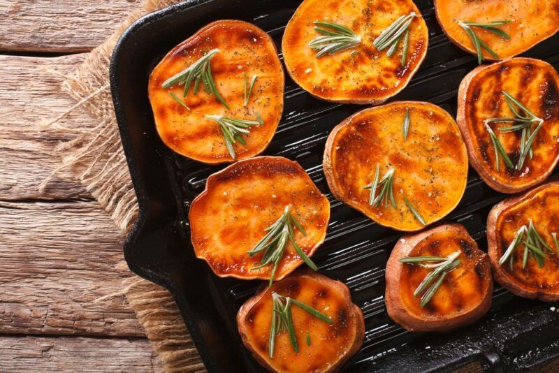 A black cast iron pan with slices of sweet potato that have been grilled