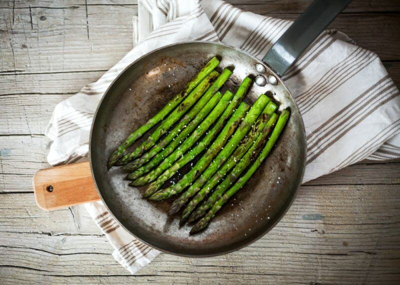 A frypan containing cooked asparagus spears