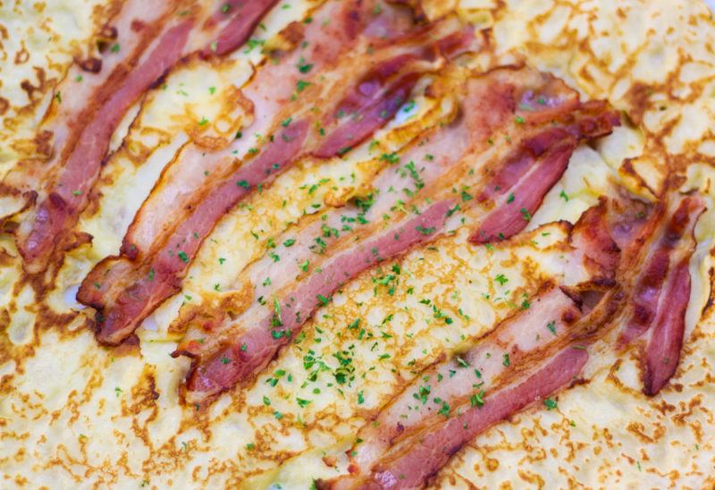 A close up image of a German pancake that includes strips of bacon