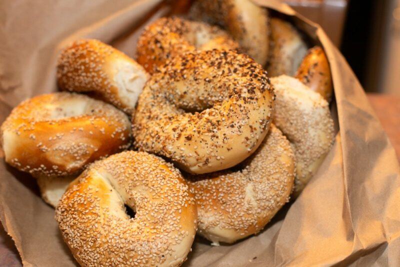 A paper bag containing many fresh New York bagels