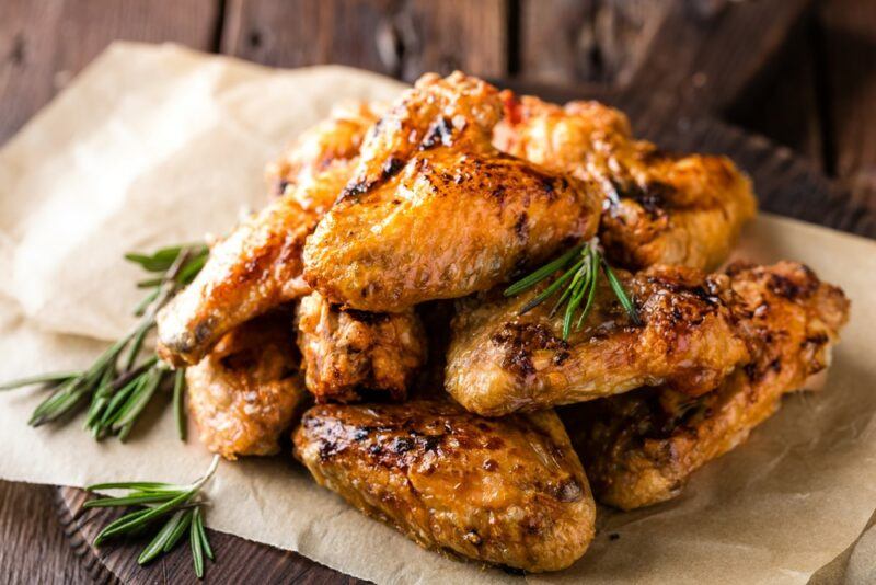 A piece of cloth with cooked chicken wings and some sprigs of rosemary