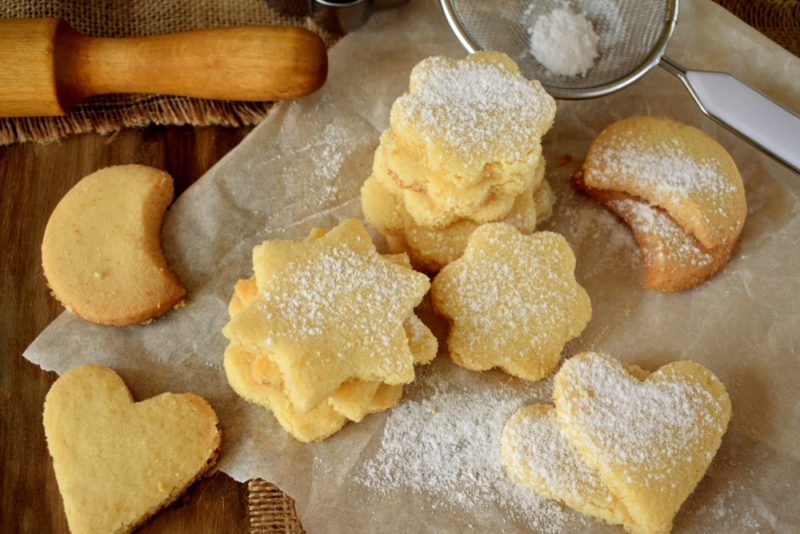 A piece of parchment paper with shortbread in different shapes, some of which are covered in sugar