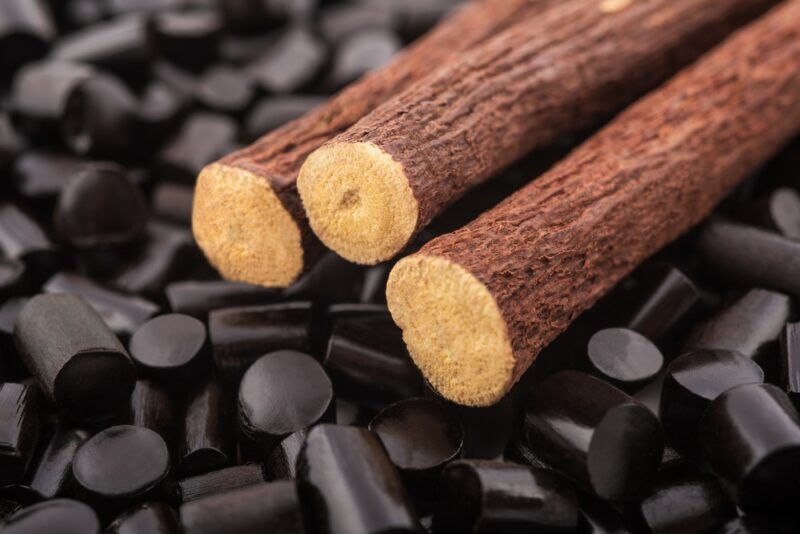 Black licorice in a pile, with licorice roots on top