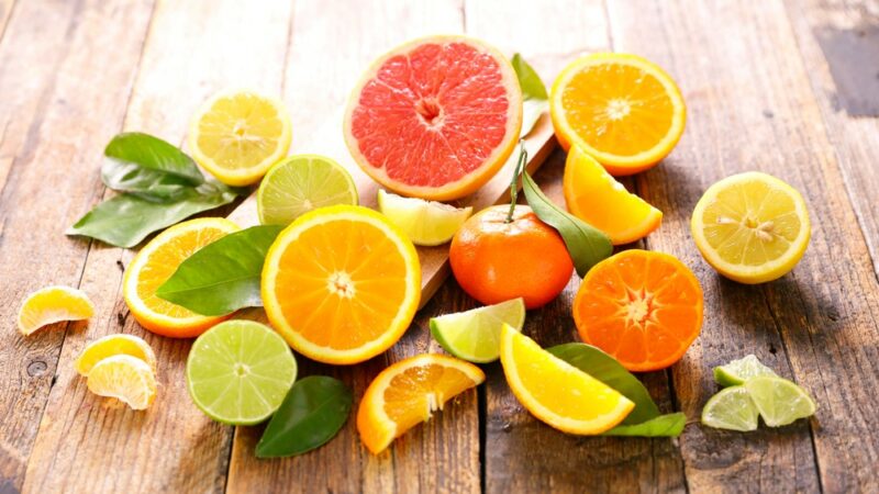 A wooden table or floor with a pile of citrus fruit