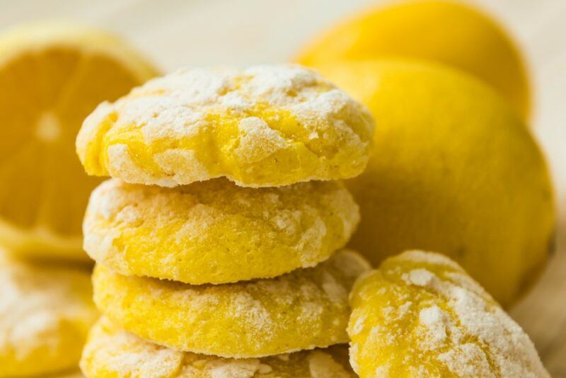 A stack of cream cheese lemon cookies with some fresh lemons and a lemon half in the background