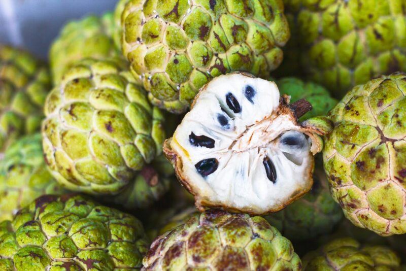 A pile of custard apples with half a custard apple sitting near the top